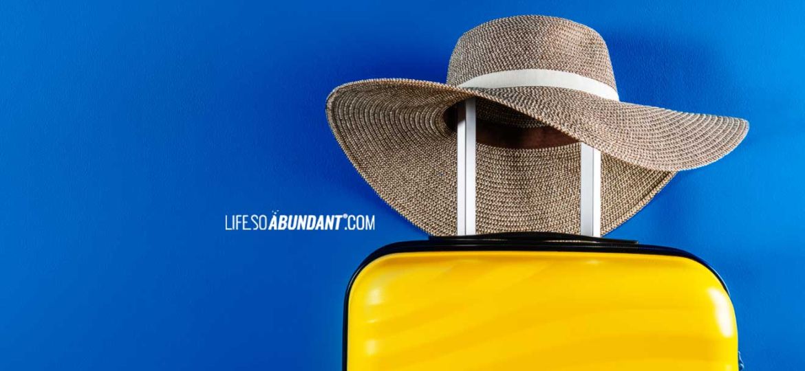 Luxury Travel Luggage - Bright yellow luxury luggage with fashionable vacation hat resting on the handle - Life So Abundant®